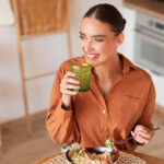 Frau isst Salat mit Smoothie