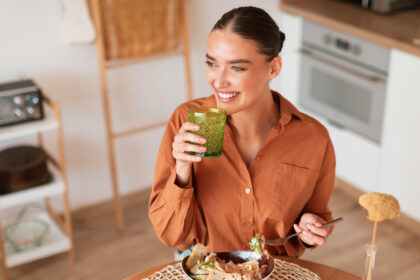 Frau isst Salat mit Smoothie