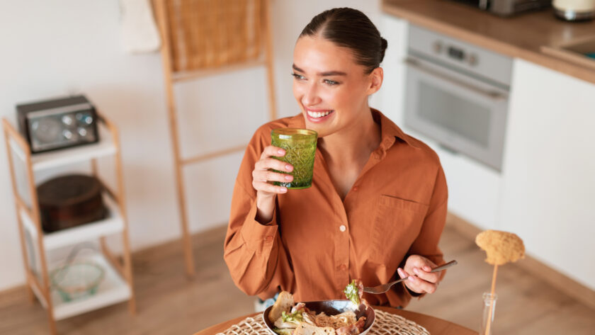 Frau isst Salat mit Smoothie