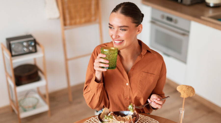 Frau isst Salat mit Smoothie