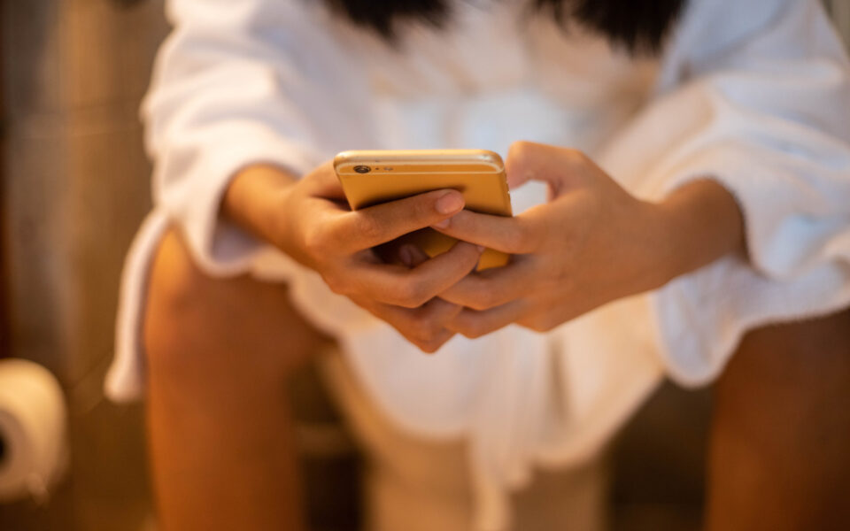 Mit Handy auf der Toilette